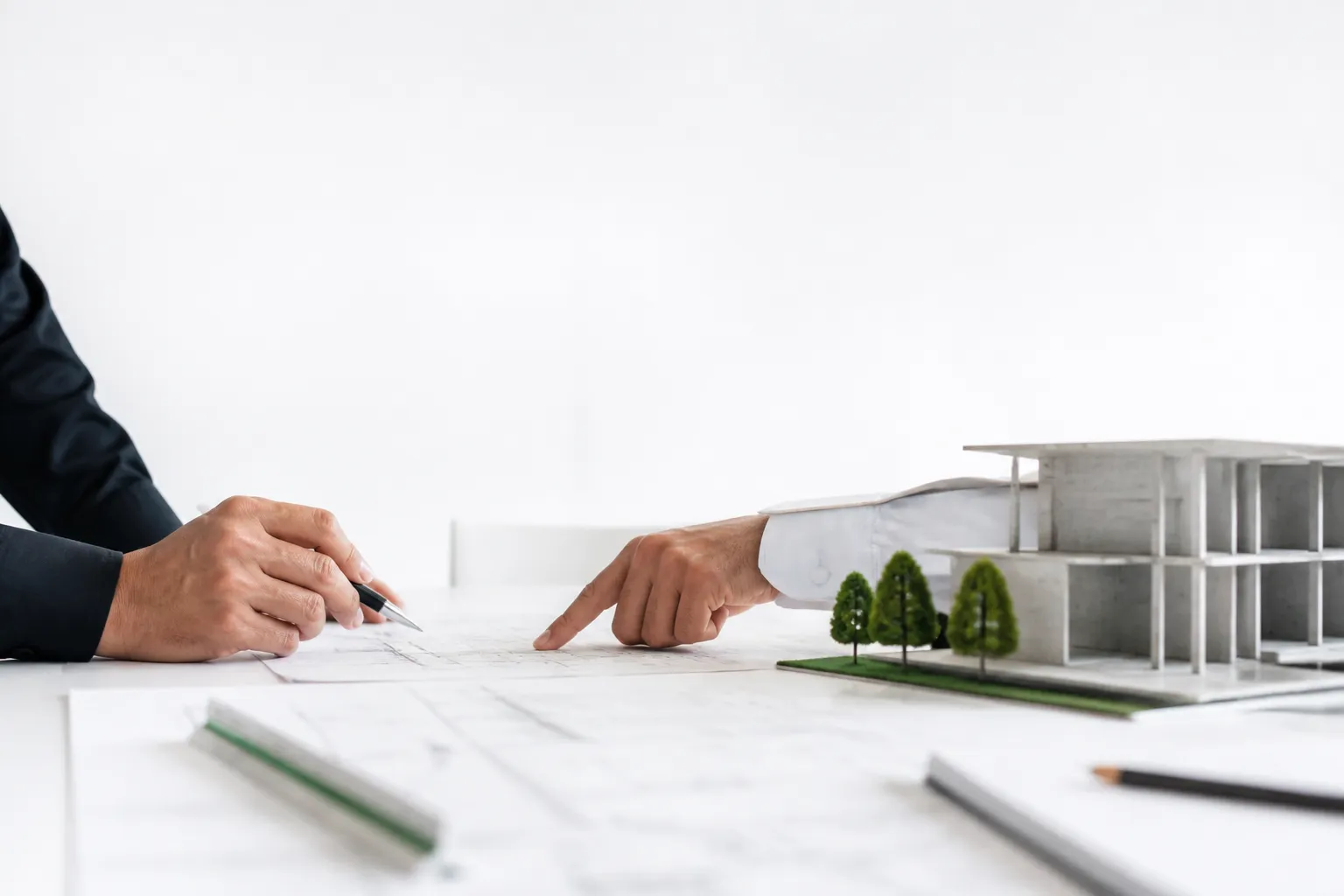 Deux professionnels relisent des plans près d’une maquette de bâtiment